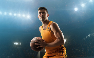 Professional basketball player on floodlit basketball arena with the ball
