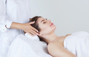 Masseur makes a relaxing massage on the face, neck and shoulders of a beautiful woman in a spa.