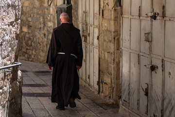 Catholic priest walking on the old narrow street in the Old city of Jerusalem
