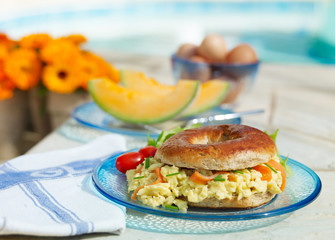 Srambled Egg and Salmon Bagel on glass platee, sunny patio location