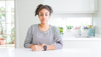 Beautiful african american woman with afro hair wearing casual striped sweater Relaxed with serious expression on face. Simple and natural looking at the camera.