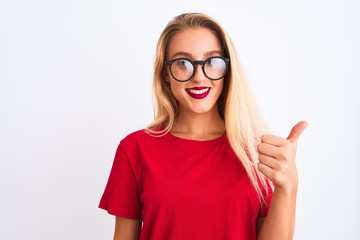 Young beautiful woman wearing red t-shirt and glasses standing over isolated white background doing happy thumbs up gesture with hand. Approving expression looking at the camera with showing success.