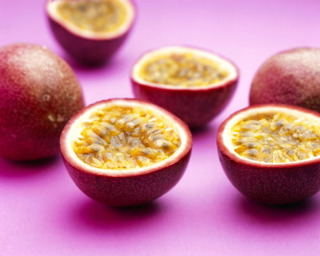 Cut and whole grenadilla against a purple background