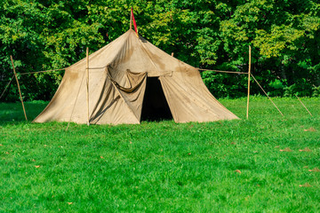 military tent in the open meadow. Against the background of trees. The concept of military training, scout movement, outdoor recreation in natural conditions.