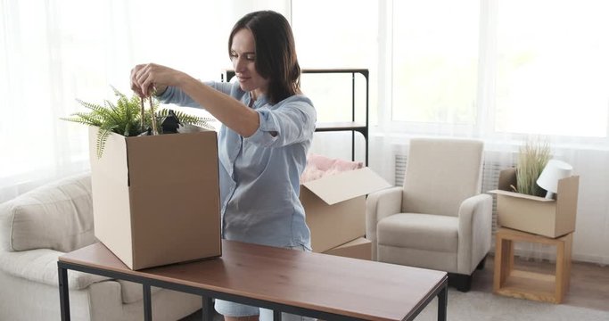 Young woman moving into new house arranging lamps on shelf