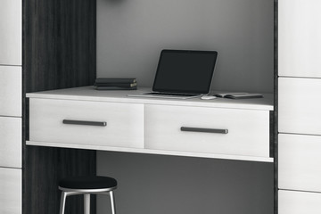 Modern style workspace with white furniture and laptop with blank screen on the table.