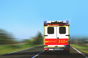 German ambulance van on highway with flashing lights -  Notruf 112-Rettungswagen in English:...