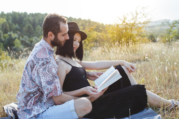 Love couple reading a book on field. Sunset.