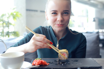 girl eats sushi and rolls in a restaurant / oriental cuisine, Japanese food, young model in a restaurant © kichigin19
