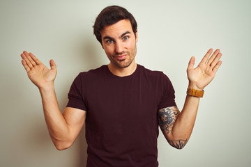 Young handsome man with tattoo wearing purple casual t-shirt over isolated white background...