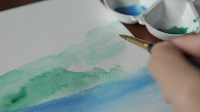 Artist paints watercolor on paper