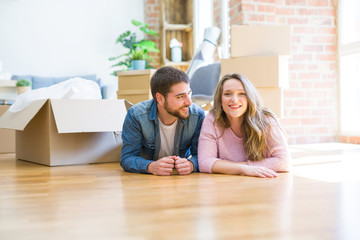 Fototapeta na wymiar Young beautiful couple in love relaxing lying on the floor together with cardboard boxes around for moving to a new house