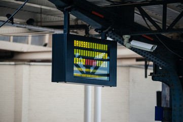 Side view of Electronic arrival departure board with city name and track inside Oostende railway station in Belgium with destination to Brussel Eupen