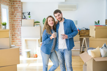 Fototapeta na wymiar Young couple relaxing from moving to a new house drinking a coffee around cardboard boxes
