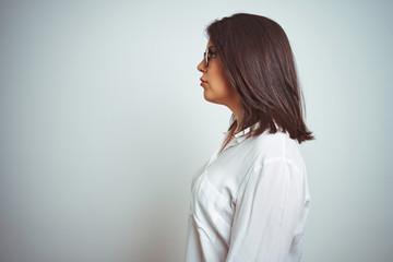 Young beautiful business woman wearing glasses over isolated background looking to side, relax profile pose with natural face with confident smile.