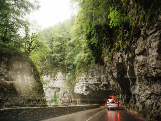 Cinematic view of car driving in Chorance in the Vercors Massif France under tall stones and fir...