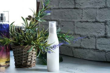The lotion white container, mockup on nature background with flowers, copy space.