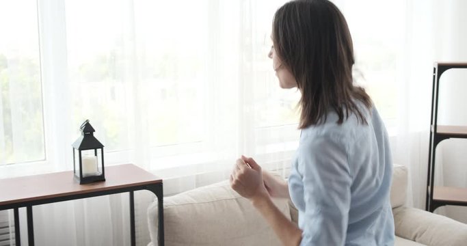 Woman moving into new house decorating plants and lamp on shelf