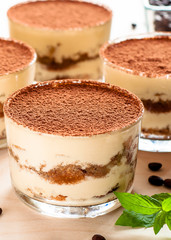 Tiramisu in the glass decorated whith mint on the wooden background