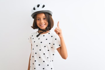 Beautiful child girl wearing security bike helmet standing over isolated white background pointing finger up with successful idea. Exited and happy. Number one.
