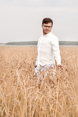 Naklejka na ściany i meble Men in a white shirt walks through a wheat field