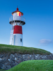 Fototapeta na wymiar white lighthouse lighting in night twilight on Faroe islands Big size