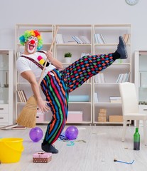Funny clown doing cleaning at home