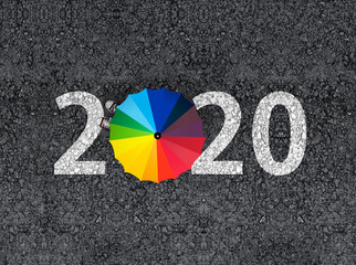 happy new year 2020. 2020 on  asphalt with man with colorful rainbow umbrella