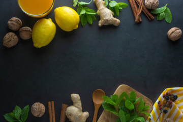 Ginger, lemons and mint leaves on dark background. Ginger tea, drink ingredients, cold and autumn time. Copy space.
