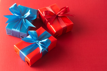 Blue and red gift boxes with red ribbon and bow isolated on red background, top view. Christms, party concept.