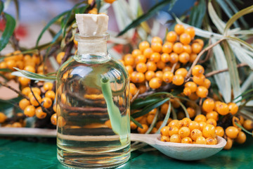 Sea buckthorn oil and Seaberries buckthorn branch in bowl on a wooden background. selective focus image