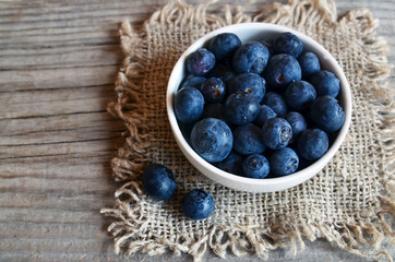Freshly picked organic blueberries in a white bowl on a burlap cloth background.Blueberry. Bilberries. Healthy eating,vegan food or diet concept.