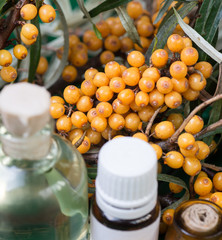 Sea buckthorn oil and Seaberries buckthorn branch in bowl on a wooden background. selective focus image