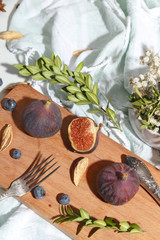 Figs, blueberries and almonds on a wooden cutting board.