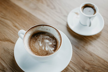 cups of cappuccino and espresso on a wooden background