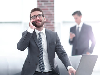 Confident young man talking on phone in office