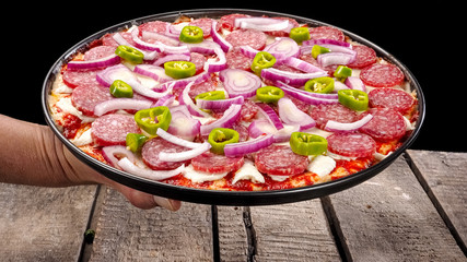 Raw pepperoni pizza on wood, close up