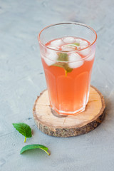 Glass of fresh red fruit juice with ice and mint on gray stone background. Food concept