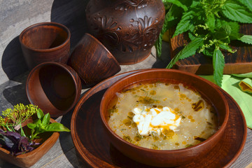 Russian cuisine: country soup with nettle on rustic table on ceramic bowl