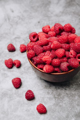clay plate with tasty bright raspberries on a gray background