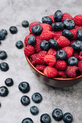clay plate with tasty bright raspberries on a gray background
