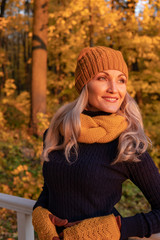 In autumn, a woman stands and looks at us not beautiful leaves in the forest, she is in a hat and...
