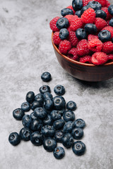 clay plate with tasty bright raspberries on a gray background