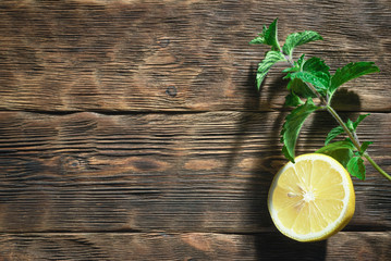 Lemon and mint leaf on a wooden cutting board background. © Natali