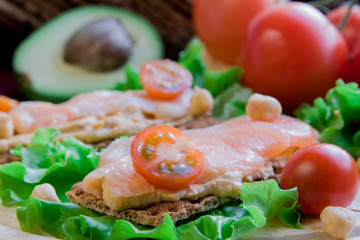 Crispbread with hummus and salmon on vegetable background