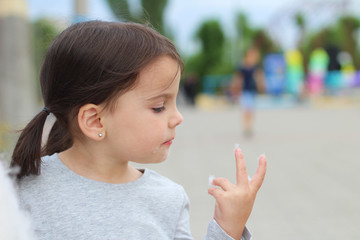 little funny white girl with ponytails licks fingers from cotton candy
