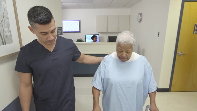 Tracking shot of male nurse and patient walking down hospital hallway