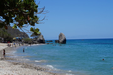 playa azul con cielo azul, paisaje vacacional, piedras magestuosas,arbol verde