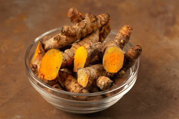 turmeric powder in jar dish on brown background
