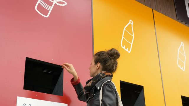 lady throws rubbish objects into pink recycling dumpster